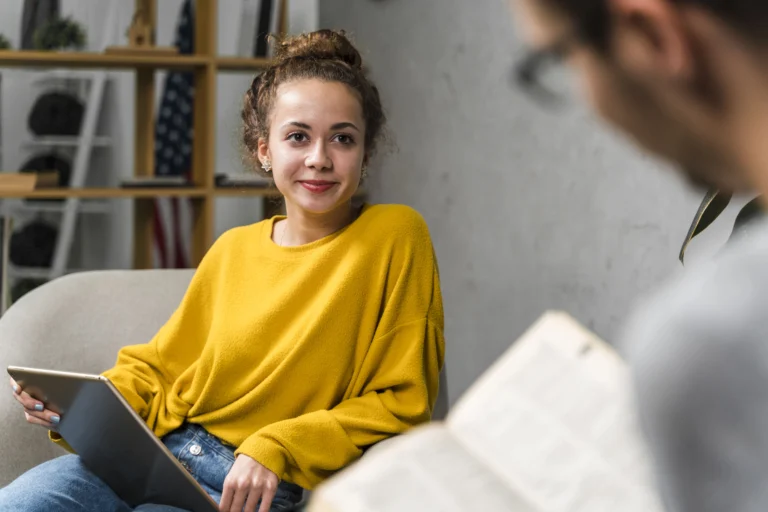 Teenage girl in a yellow sweater smiling at her therapist during a session