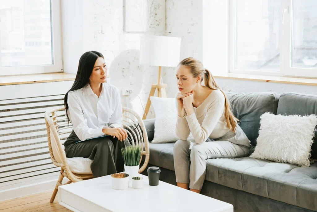 Therapist listening to a young woman sitting on a sofa